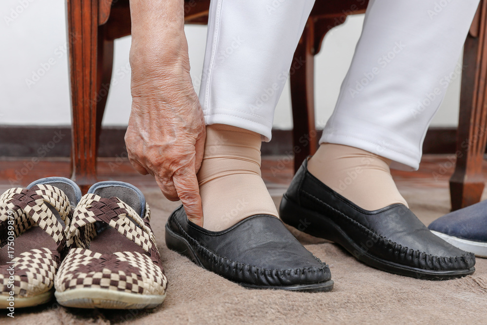 Elderly woman putting on shoes