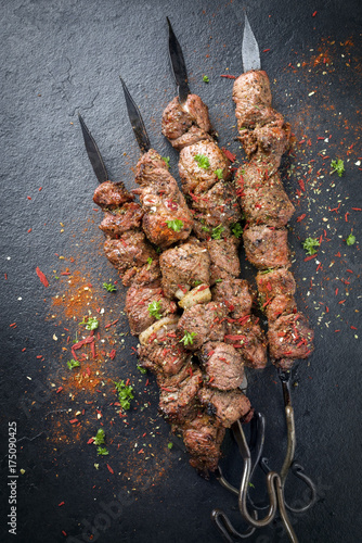 Traditional Russian shashlik on a barbecue skewer as top view on slate slab