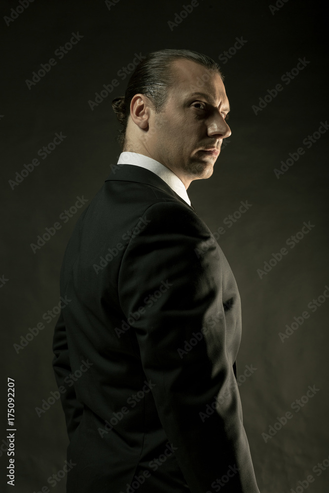 The attractive man in black suit on dark background