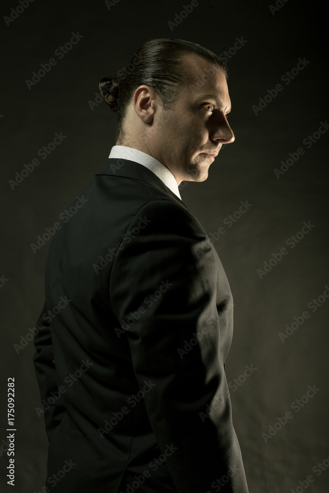 The attractive man in black suit on dark background