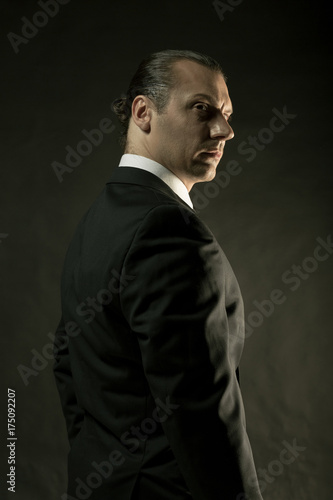 The attractive man in black suit on dark background © master1305