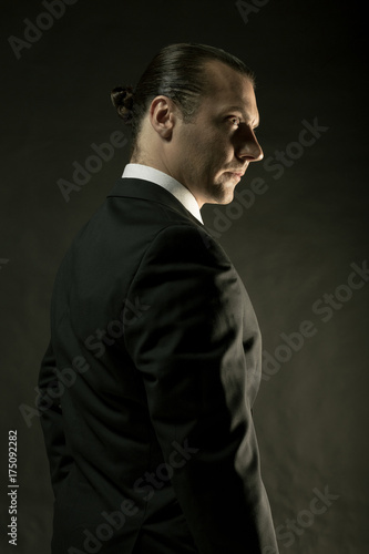 The attractive man in black suit on dark background © master1305