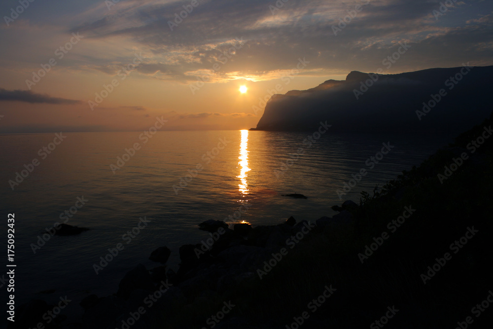 The sun and the sunset over the sea. the mountains in the background. Horizontal frame