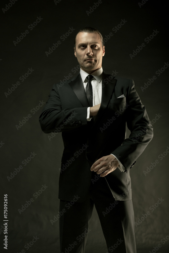 Fototapeta premium The attractive man in black suit on dark background