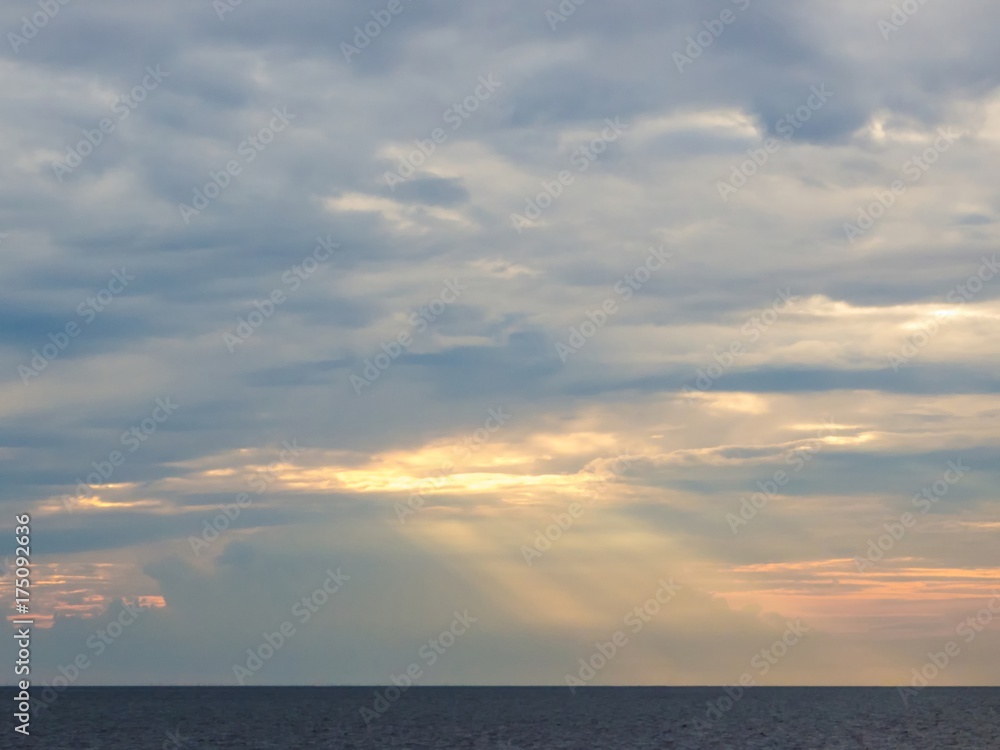 White clouds with gold sunlight ray shining over the sea.