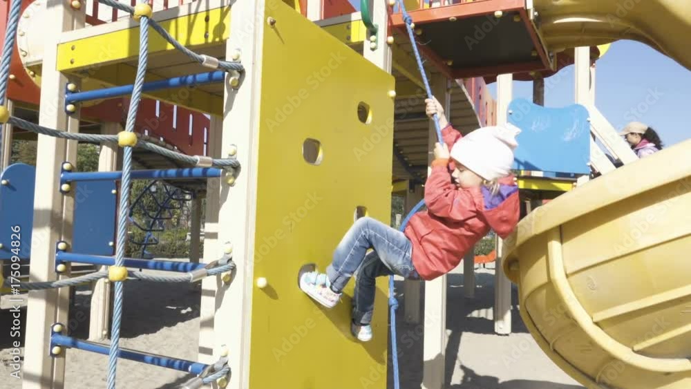 Cute little girl is climbing up on ladder in playground equipment Cute little girl is climbing up on ladder in playground equipment