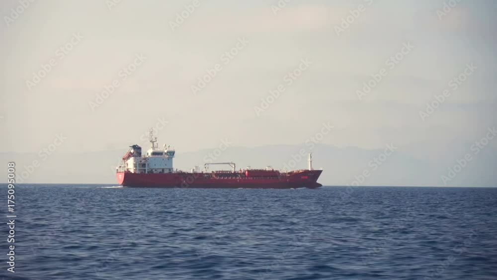 Side view of red cargo ship floating in the sea Side view of red cargo ship floating in the sea