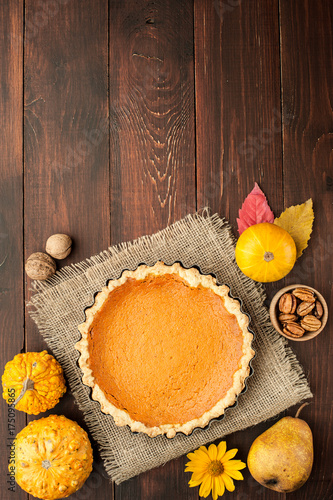 pumpkin homemade pie at wooden background arranged with food ingredients top view