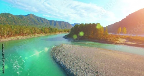 4k (UHD) aerial view. Low flight over fresh cold mountain river at cloudy summer morning. Green trees and sun rays on horisont. Fast horizontal movement