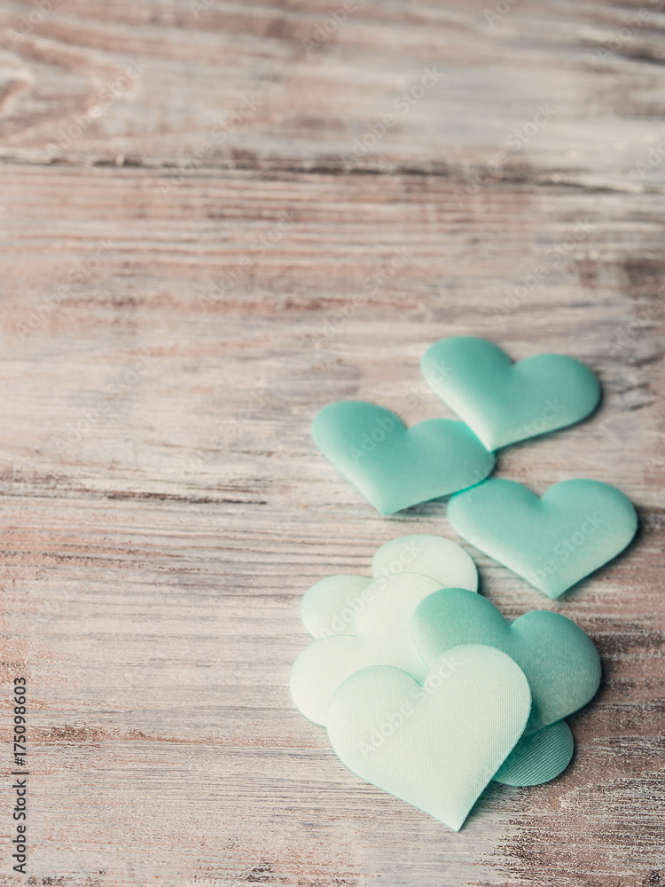 Fototapeta premium Green pastel hearts on textured wooden table. Valentine's day or baby birthday greeting card. toned