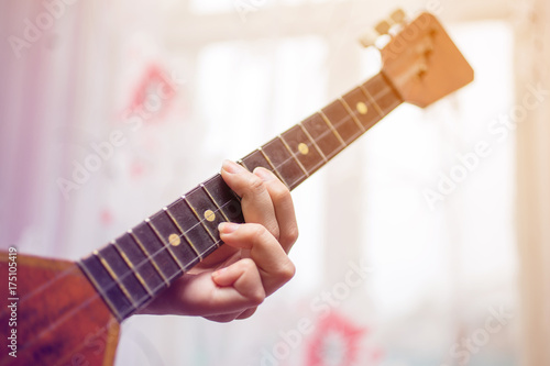 the fingers on the strings of the balalaika closeup photo