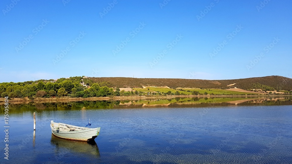 specular reflection on the calm pond with a fisherman boat