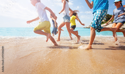 Sticker Close-up of running kids legs in shallow sea water