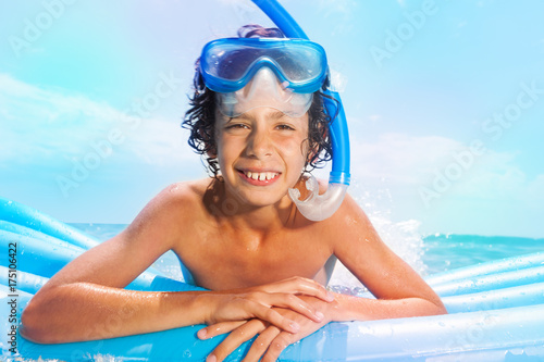 Boy with scuba mask swim on matrass in the sea photo