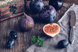 The fig is cut on a wooden table with grapes and plums. Still life with figs. Selective focus