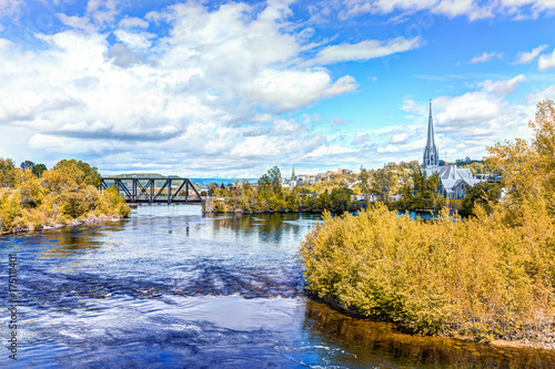 Cityscape or skyline of city in Quebec with Chicoutimi river and water flowing in autumn with bridge and church photo