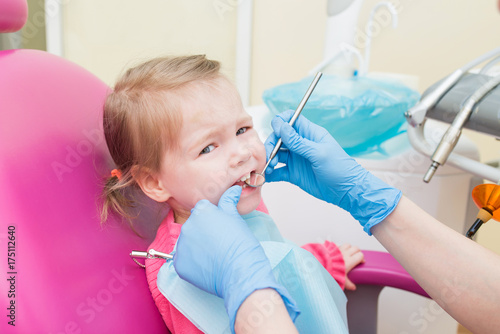 Cute Little girl sitts in dental chair at dentist office, closeup portrait