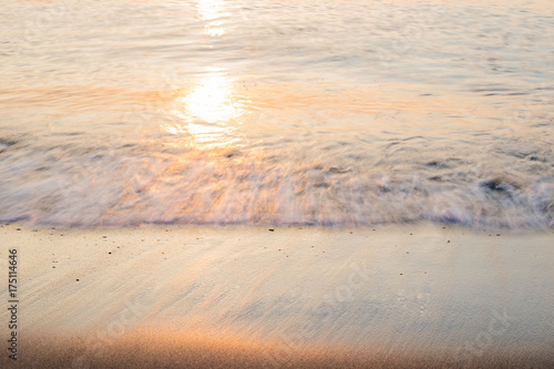 Sunset soft beautiful ocean wave on sandy beach. romantic travel background.