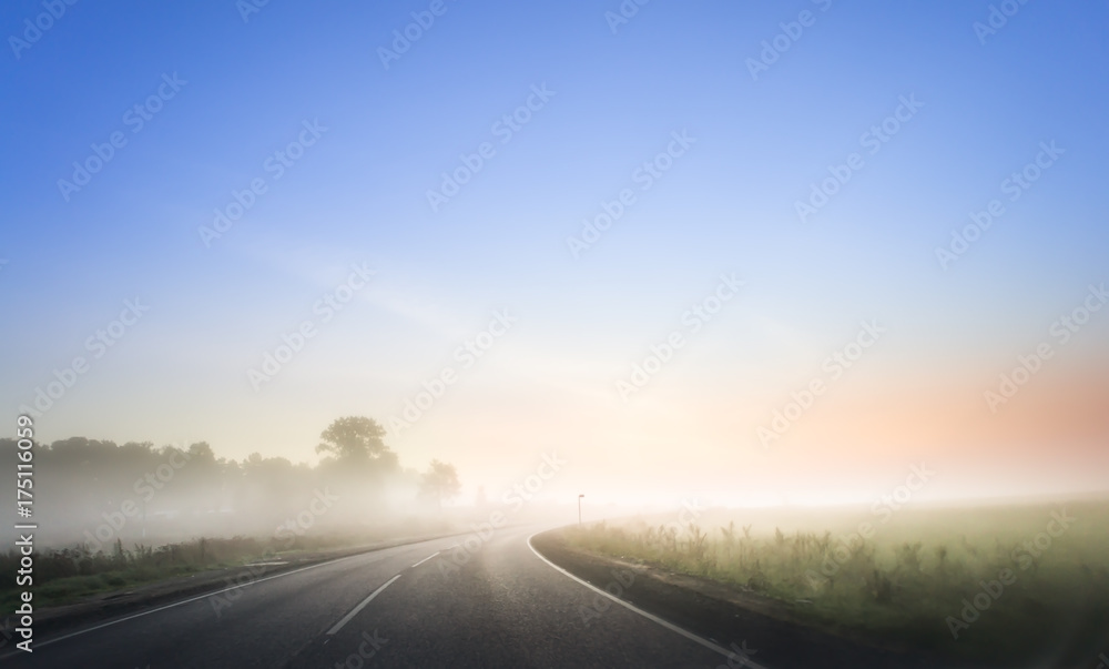 Nice winding road caught in the fog in winter time. Morning with red sunrise