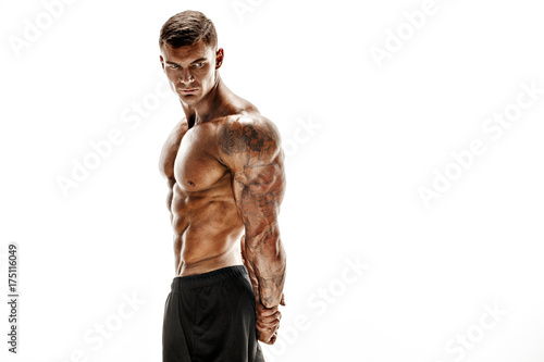 Fototapeta Tattooed muscular super-high level handsome man posing in studio isolated on whi
