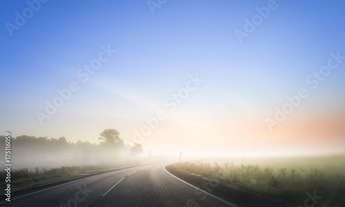 Nice winding road caught in the fog in winter time. Morning with red sunrise