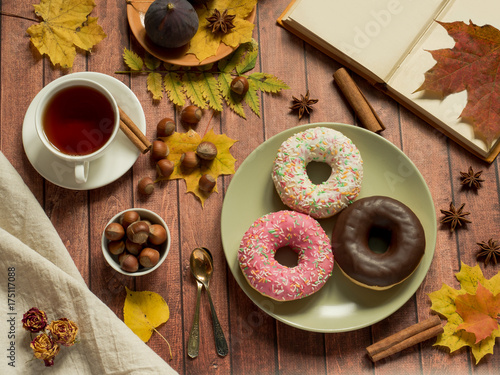Colorful donuts on plate autumn and a Cup of tea, the layout on rustic wooden background.