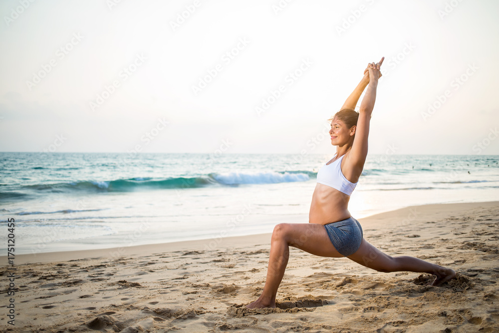 Natural looking pregnant woman practicing yoga at the seashore at sunset Natural looking pregnant woman practicing yoga at the seashore at sunset