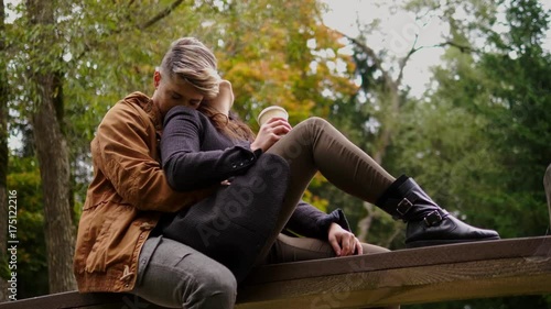 Lovely couple sitting on wooden bridge in autumn park