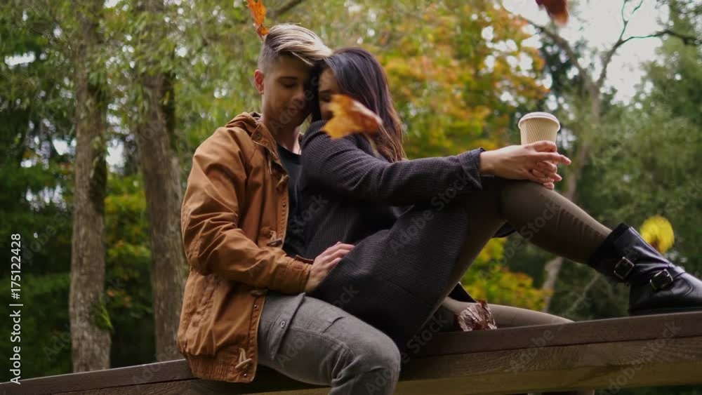 Lovely couple sitting on wooden bridge in autumn park Lovely couple sitting on wooden bridge in autumn park