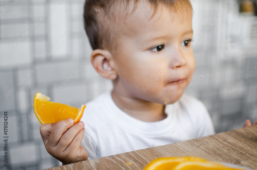 The child in the kitchen eating an orange The child in the kitchen eating an orange