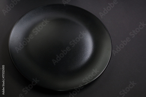 An empty black plate on a black background