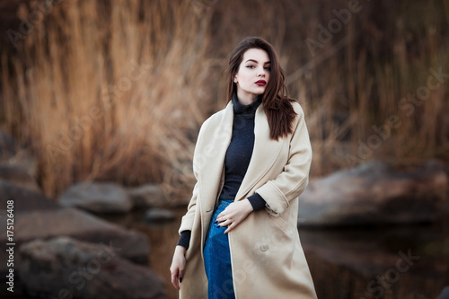 Portrait of a Stylish Pretty Young Woman in Autumn Fashion Coat walking outdoors.