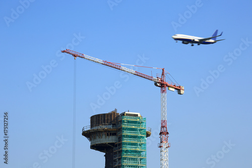 Budowa terminala na lotnisku, przelatujący samolot.