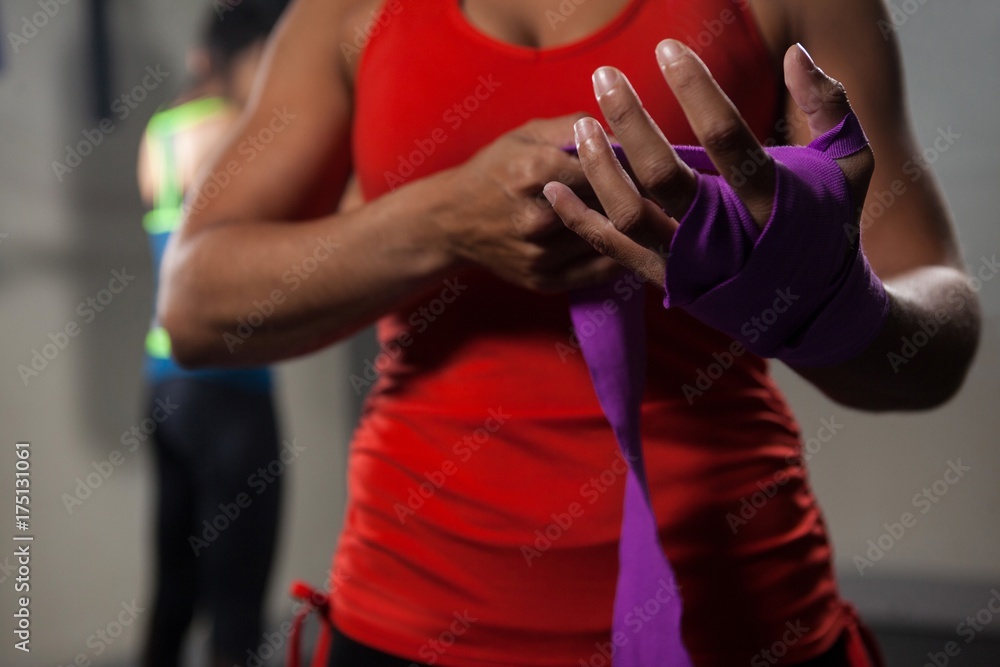 Obraz premium Mid section of woman tying hand wrap on hand