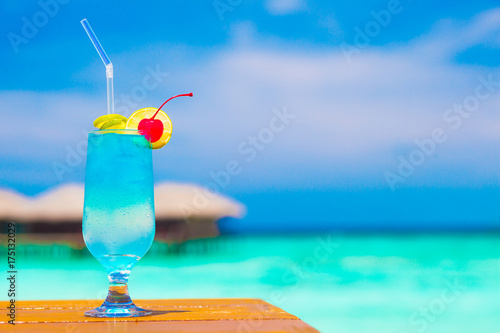Bild auf Leinwand glass of blue curacao cocktail with cherry by the beach