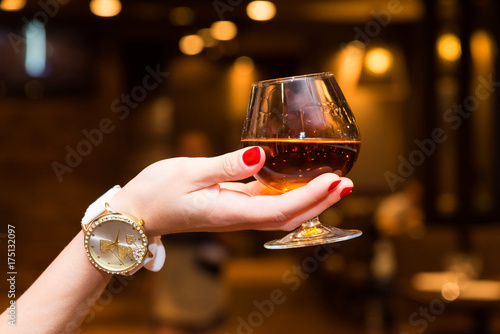 The girl's hand holds a glass of cognac photo