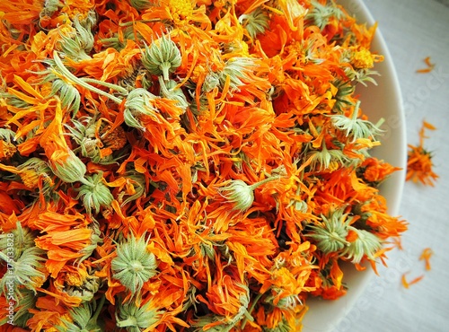 Dry calendula marigold flowers in a bowl on white linen napkin.