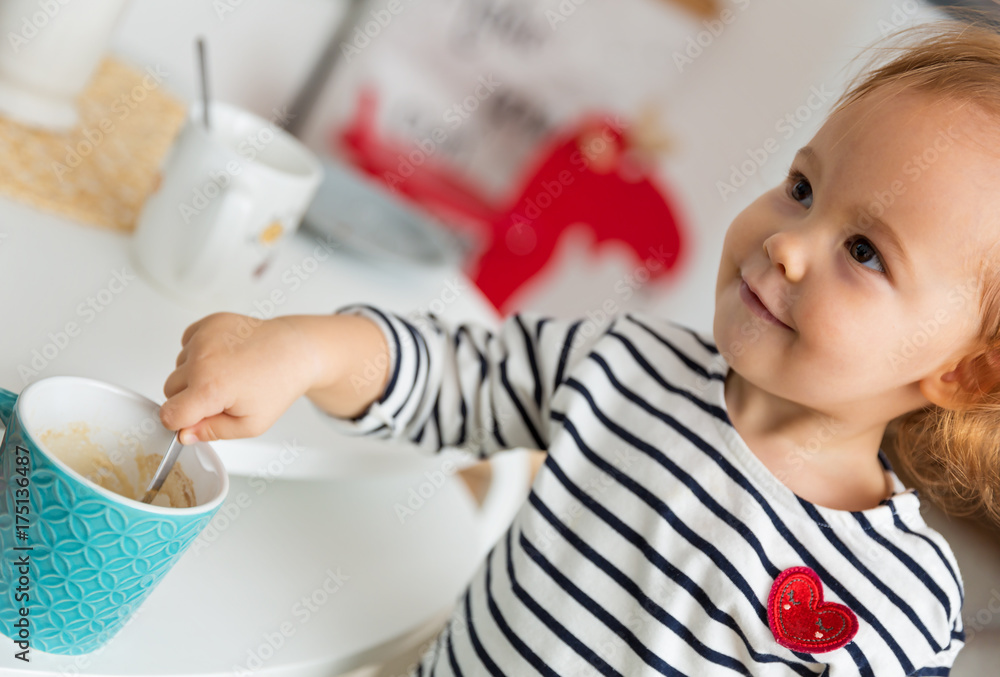 Eighteen months old toddler mixing the coffee in the mug and playing with the cup on the desk Eighteen months old toddler mixing the coffee in the mug and playing with the cup on the desk