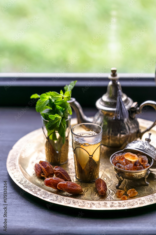 Moroccan tea with mint and sugar in a glasses on a copper plate with kettle Moroccan tea with mint and sugar in a glasses on a copper plate with kettle