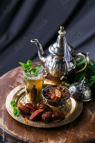 Glass of mint tea with dates and sugar, on copper plate
