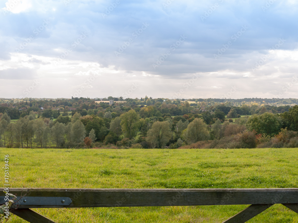 countryside hill field above wooden gate with trees and sky countryside hill field above wooden gate with trees and sky