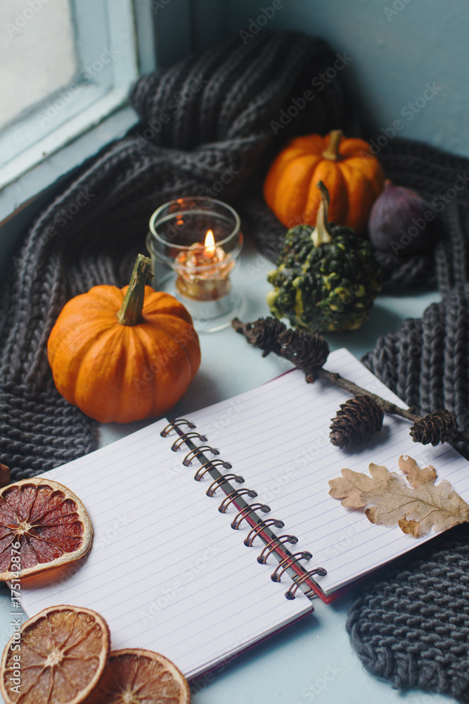 Cozy autumn background, notebook, decorative pumpkins, dried oranges, candle, nuts, cinnamon and autumn leaves Cozy autumn background, notebook, decorative pumpkins, dried oranges, candle, nuts, cinnamon and autumn leaves