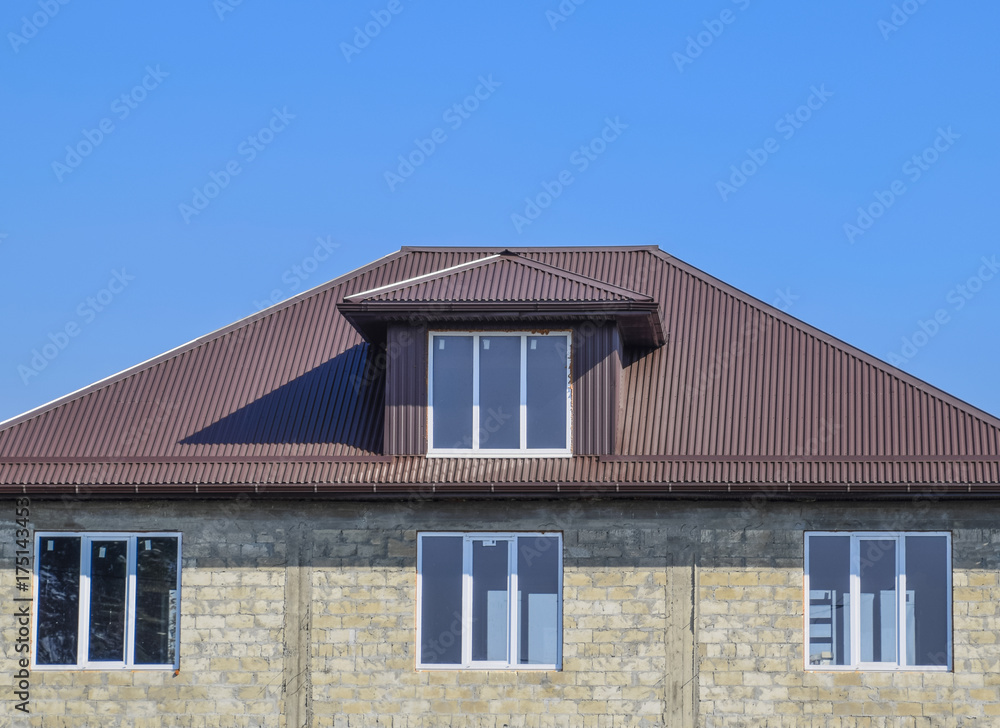 House of cinder block. House with plastic windows and roof of corrugated sheet. Roofing of metal profile wavy shape on the house with plastic windows