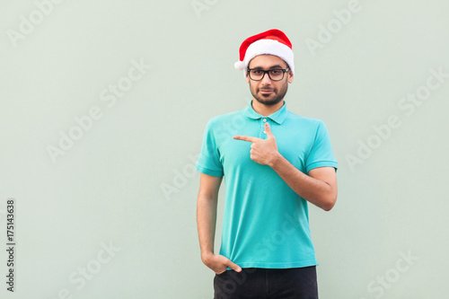 Businessman pointing copy space. Handsome man with beard in blue shirt looking at camera and pointing away while standing isolated on gray background