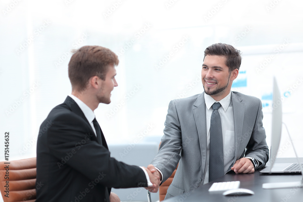 handshake of business partners sitting at a Desk. handshake of business partners sitting at a Desk.