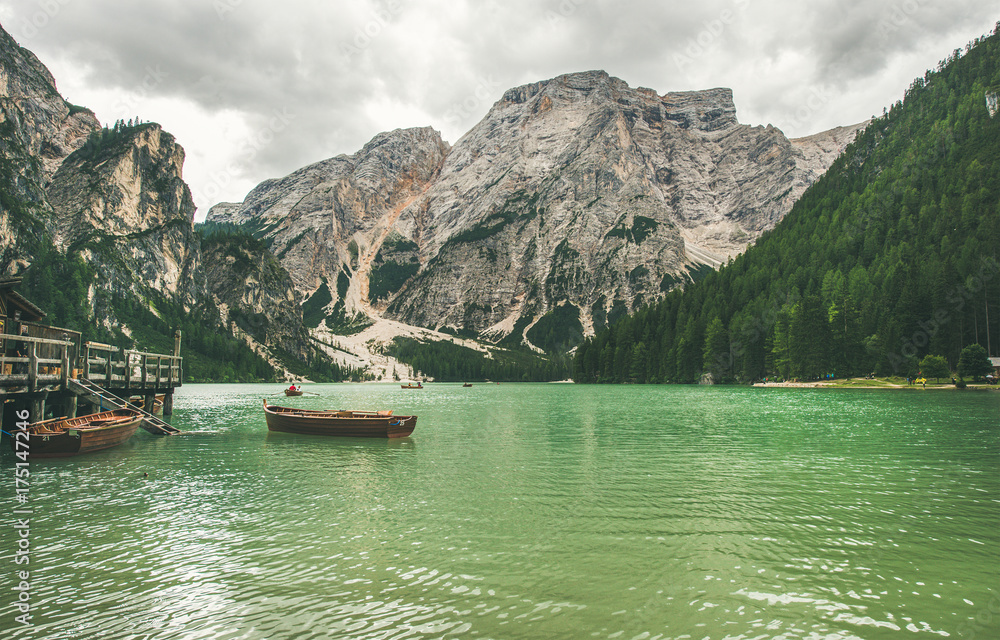 Lago di Braies or Pragser Wildsee in Fanes-Sennes-Braies Nature Park. Mountain lake with clear emerald waters and wooden boats in Valle di Braies in Dolomite Alps in North Italy on gloomy day