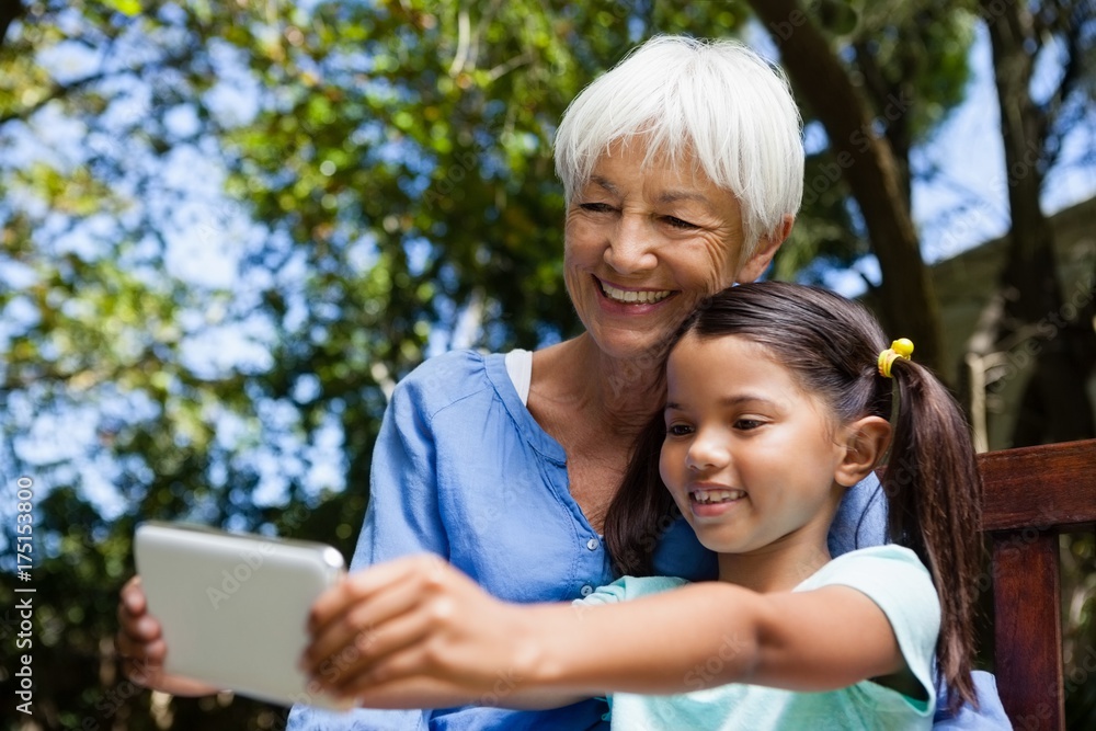 Smiling grandmother and granddaughter taking selfie while Smiling grandmother and granddaughter taking selfie while