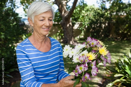 Smiling senior woman holding fresh flower bouquet