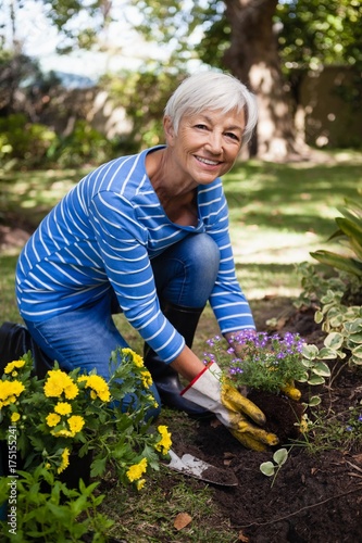 Portrait of smiling senior woman planting flowers