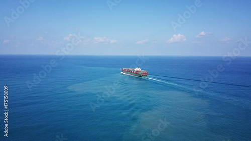 Huge large mega container ship sails on open water fully loaded with containers and cargo - aerial view